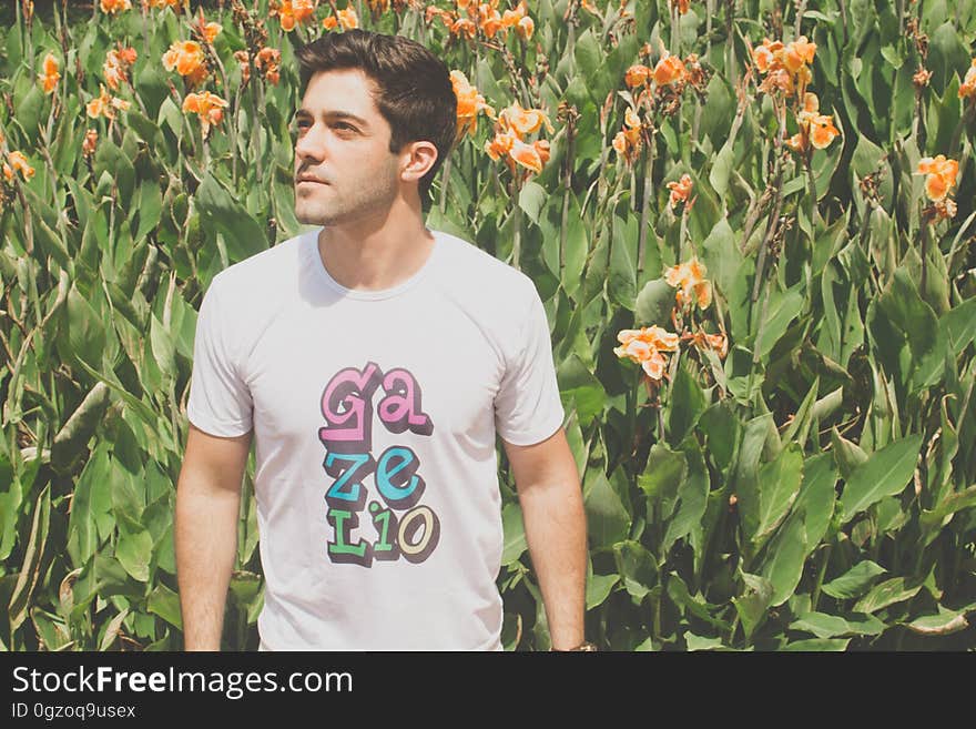 A man standing in a garden with a flowerbed in the background. A man standing in a garden with a flowerbed in the background.