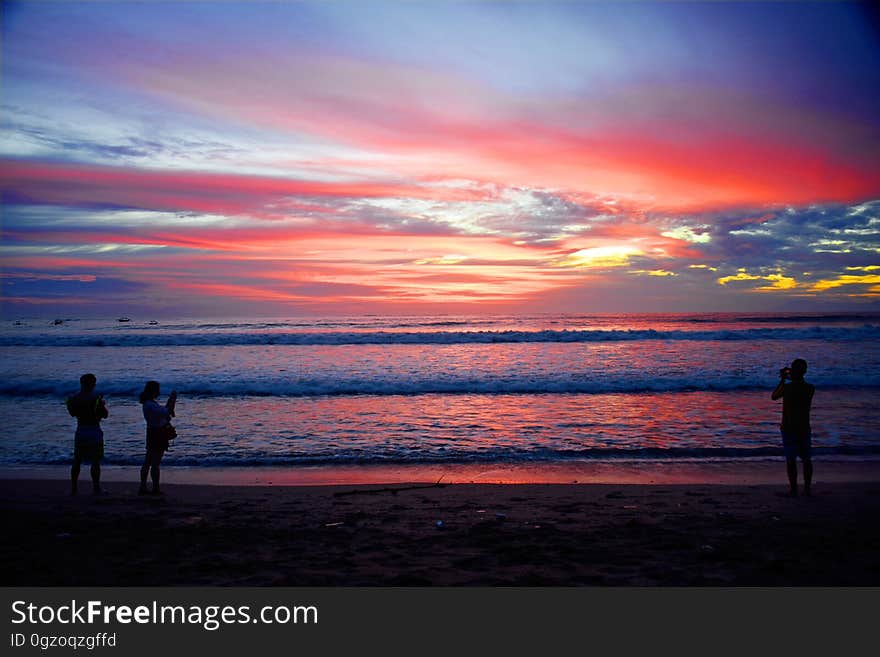 Silhouette of people standing on sandy Bali beach at sunset. Silhouette of people standing on sandy Bali beach at sunset.