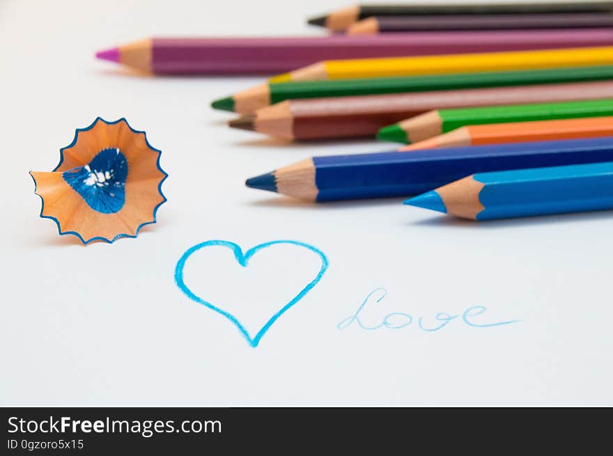 Colored pencils on white with shaving and heart drawn in blue with text love. Colored pencils on white with shaving and heart drawn in blue with text love.