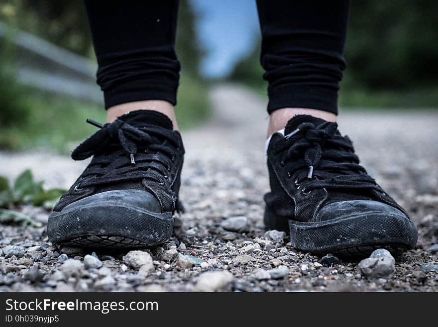 Close up of feet wearing black sneakers standing on rocks outside. Close up of feet wearing black sneakers standing on rocks outside.