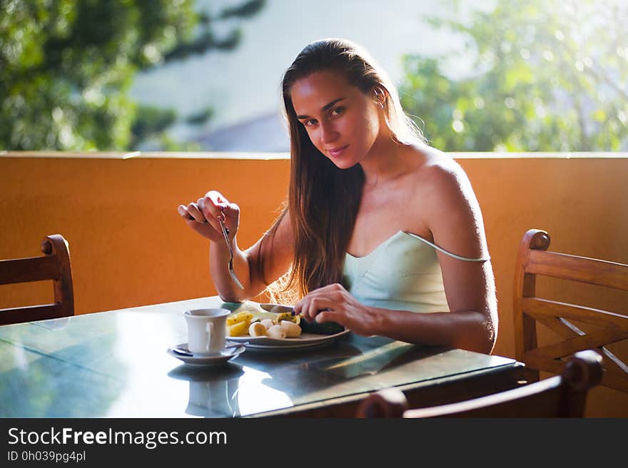 Portrait of woman seated at outdoor table eating meal. Portrait of woman seated at outdoor table eating meal.