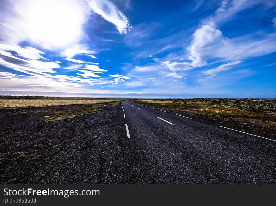 Country road through rural fields with blue skies on sunny day. Country road through rural fields with blue skies on sunny day.