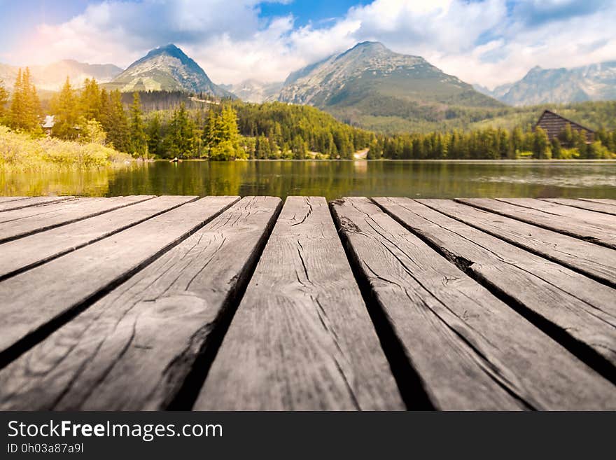 Scenic view of lake, forest and mountains with wooden pier in foreground. Scenic view of lake, forest and mountains with wooden pier in foreground.