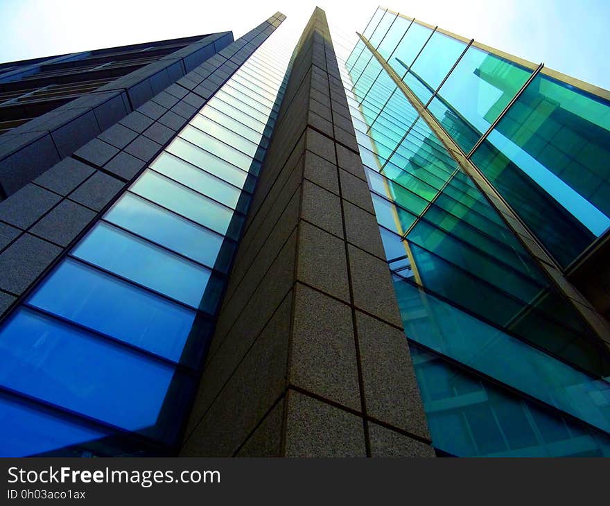 Low angle on glass and steel modern high rise architecture against blue skies on sunny day. Low angle on glass and steel modern high rise architecture against blue skies on sunny day.