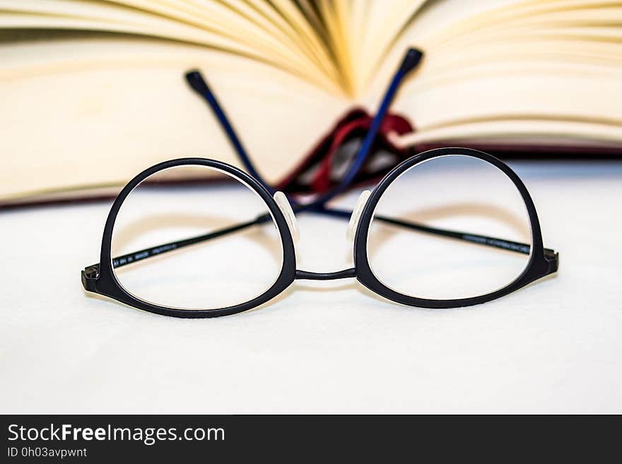 Close up of eyeglasses in front of blurred open book. Close up of eyeglasses in front of blurred open book.