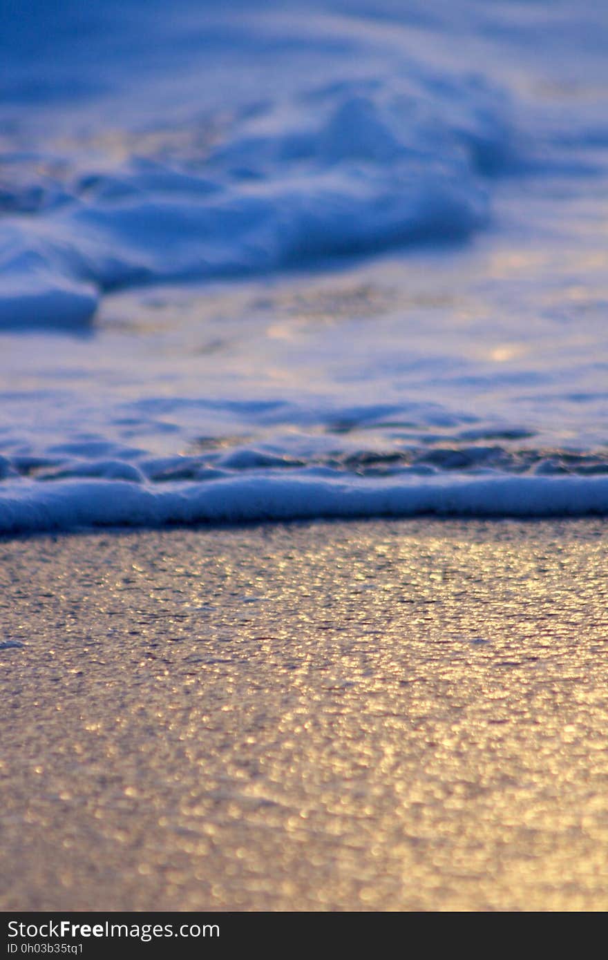 A foaming wave hitting the sand on a beach. A foaming wave hitting the sand on a beach.