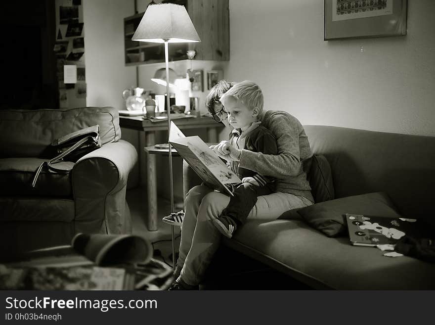 A woman reading with a baby on the sofa. A woman reading with a baby on the sofa.