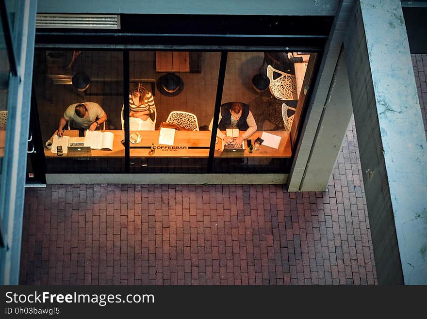 A high angle view through the window of a coffee shop with people sitting inside. A high angle view through the window of a coffee shop with people sitting inside.