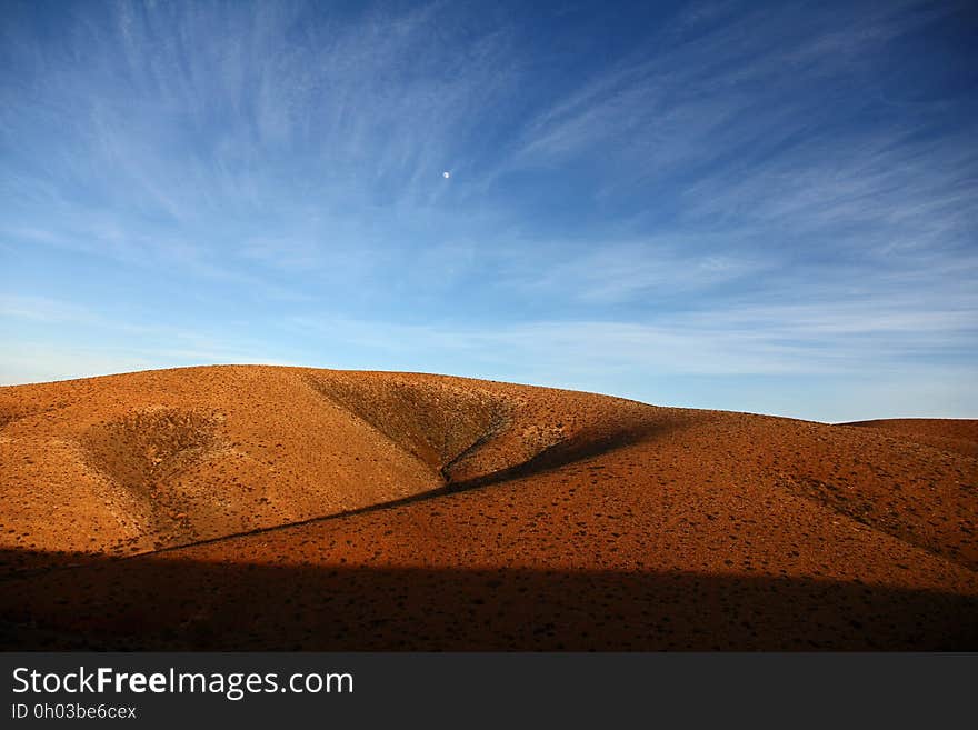 A landscape with dry red hills and blue skies.