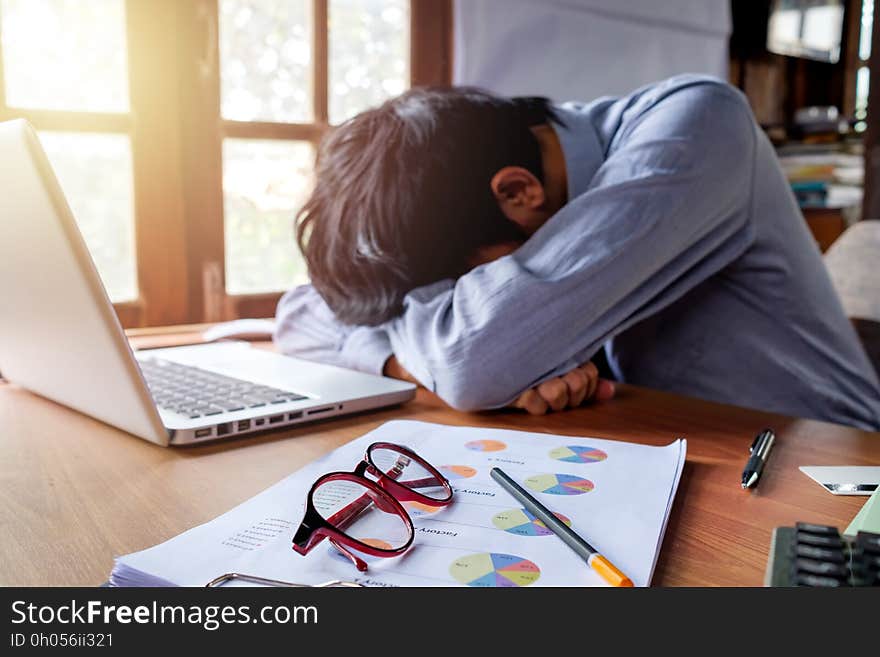 Tired businessman having long working day and sleeping on desk table with analysis chart or graph.Business analysis and strategy concept.Close up