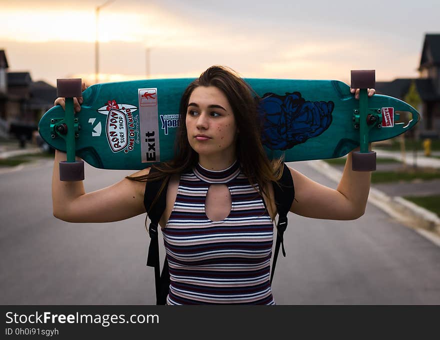 A woman holding a longboard on her shoulders. A woman holding a longboard on her shoulders.