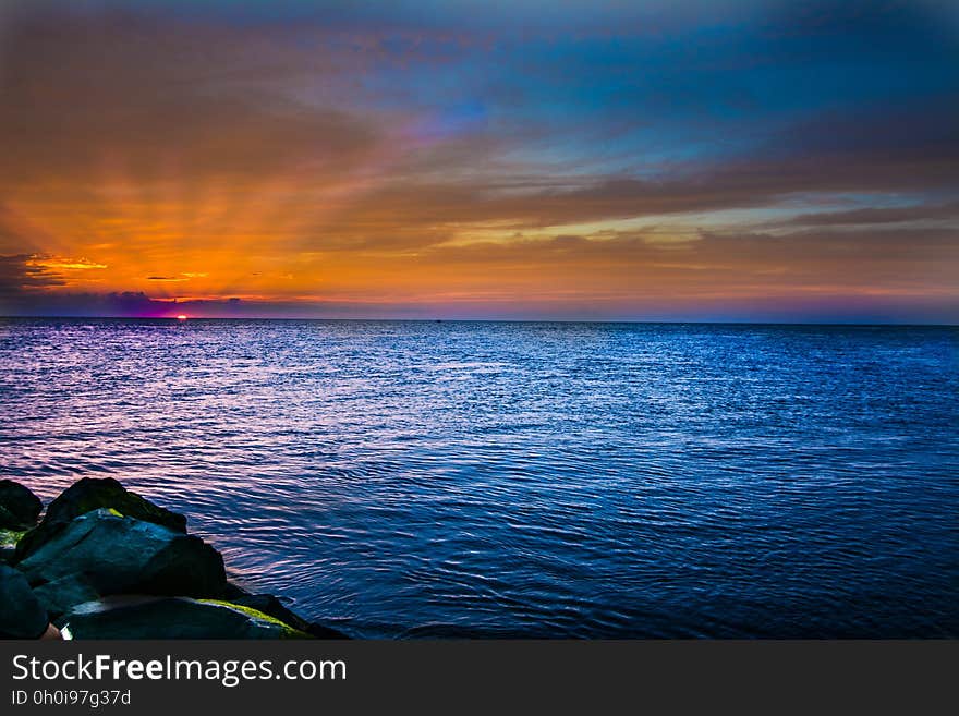 A sea scene with the sun disappearing behind the horizon. A sea scene with the sun disappearing behind the horizon.