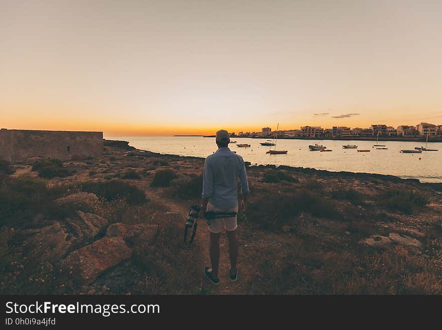 A man standing on a beach looking at a city across water. A man standing on a beach looking at a city across water.