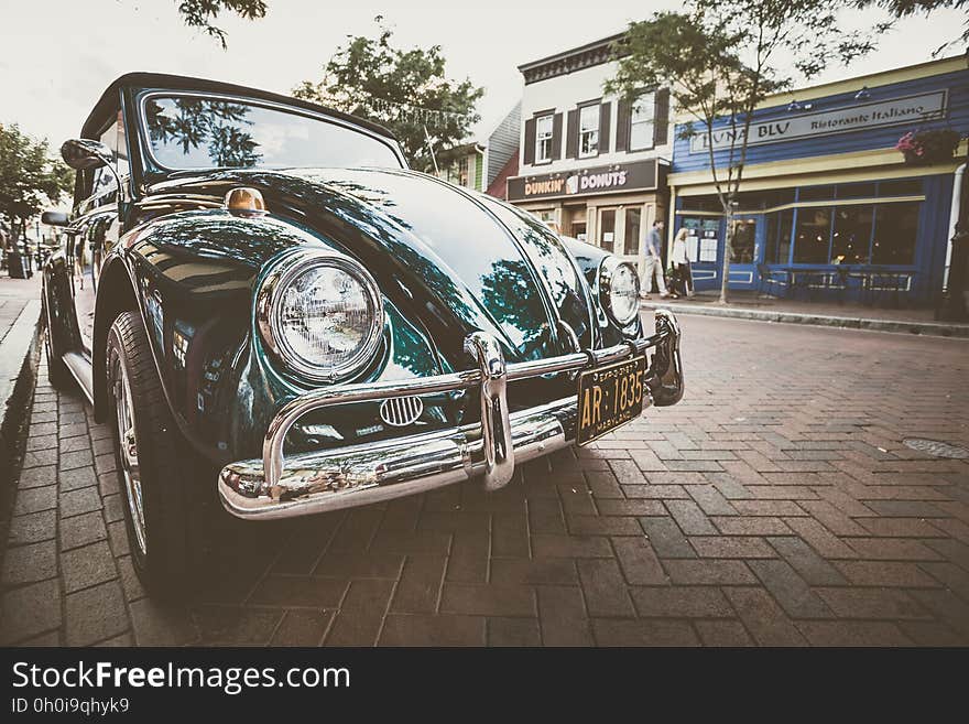 Vintage green car parked at curb on streets in front of shops. Vintage green car parked at curb on streets in front of shops.