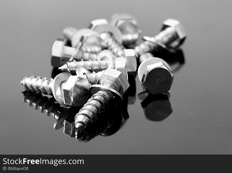 Close up of screws with washer on reflective surface in black and white. Close up of screws with washer on reflective surface in black and white.