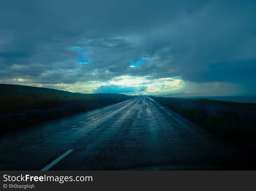 Empty roadway in countryside with blue storm clouds in sky. Empty roadway in countryside with blue storm clouds in sky.