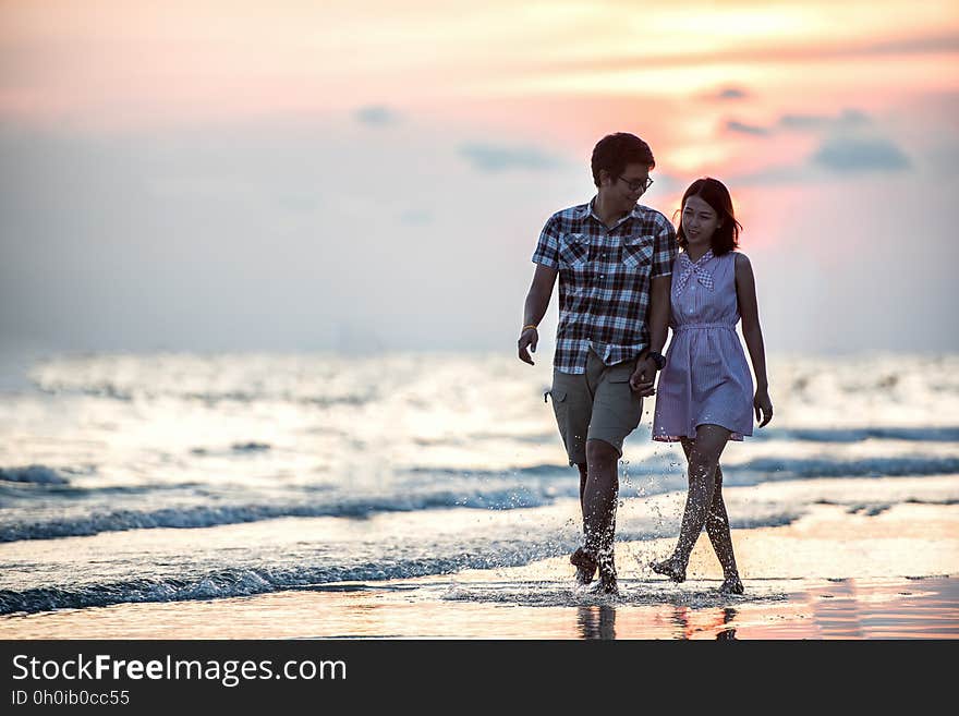 Couple holding hands strolling on beach at sunset. Couple holding hands strolling on beach at sunset.