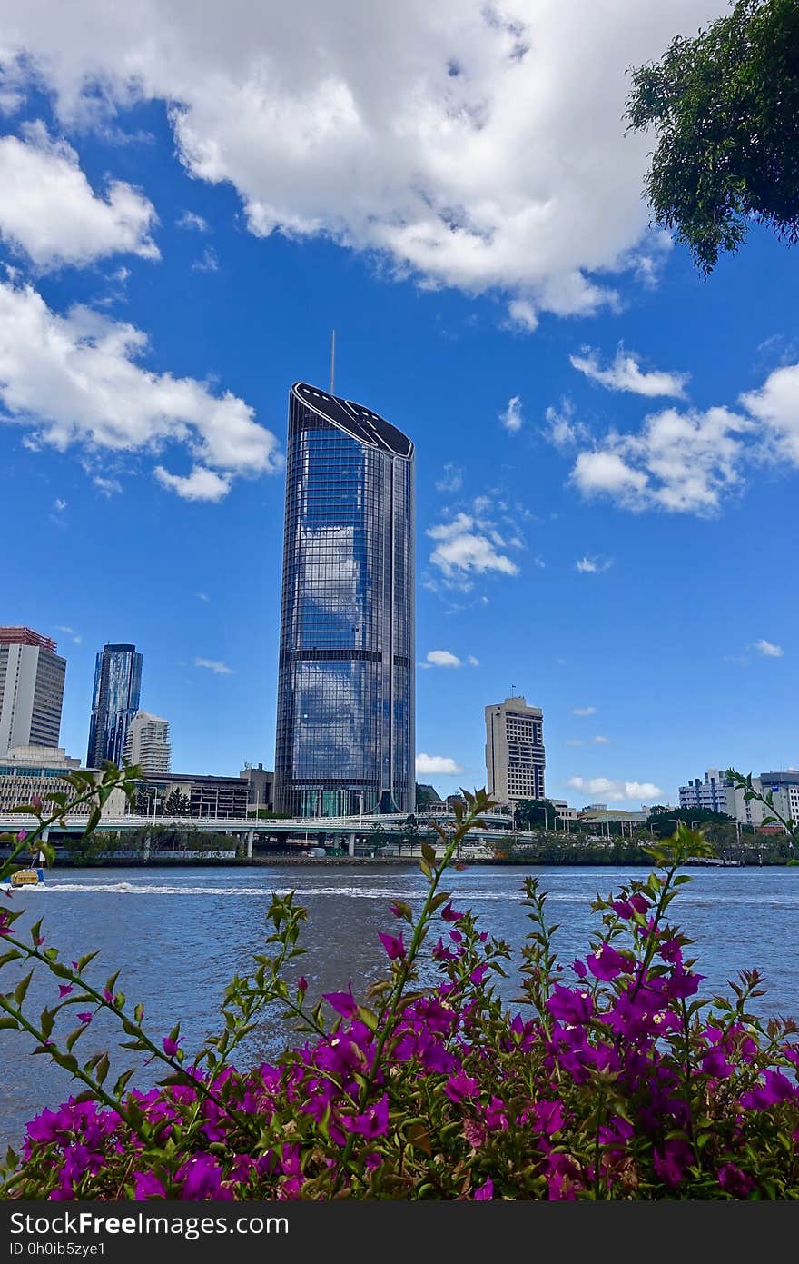 Exterior of steel and glass skyscraper in city skyline along waterfront against blue skies on sunny day. Exterior of steel and glass skyscraper in city skyline along waterfront against blue skies on sunny day.