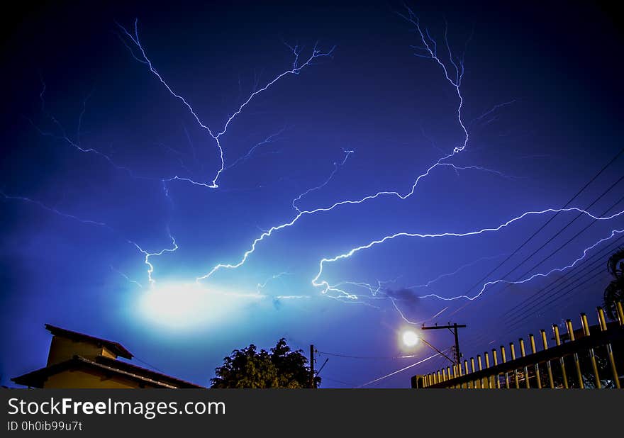 Dramatic lightning bolts in blue night sky above modern buildings. Dramatic lightning bolts in blue night sky above modern buildings.