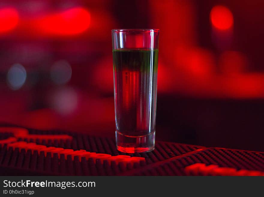 A shot glass with liquor on the bar counter. A shot glass with liquor on the bar counter.