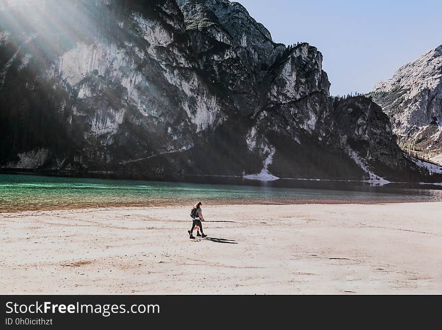 A hiker walking on a sandy beach with mountains in the distance. A hiker walking on a sandy beach with mountains in the distance.