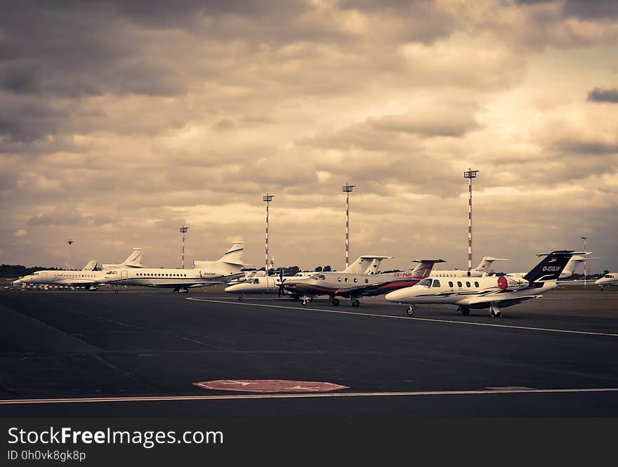 Airbus and several small private jet aircraft parked on the apron at a commercial airport, cloudy overcast sky. Airbus and several small private jet aircraft parked on the apron at a commercial airport, cloudy overcast sky.