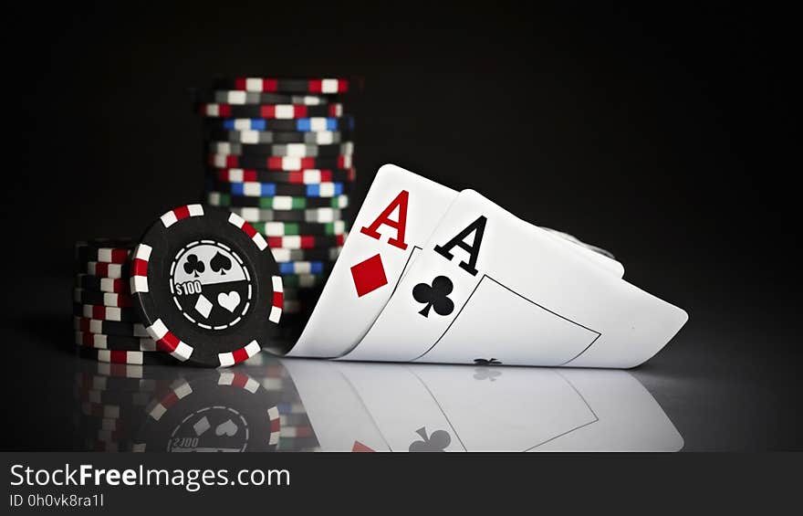 A pair of aces and stacks of gambling chips reflecting on a glass surface.