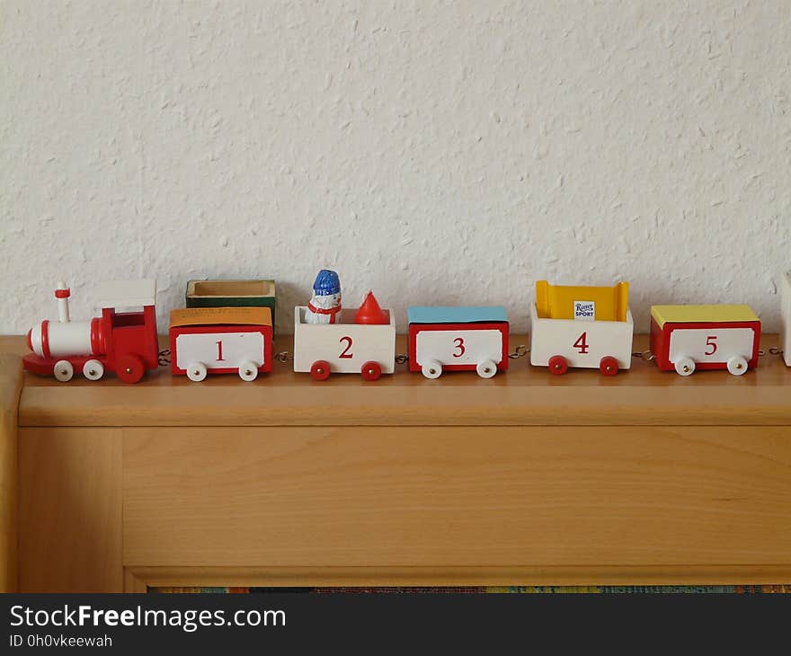 A colorful toy train on a wooden shelf.