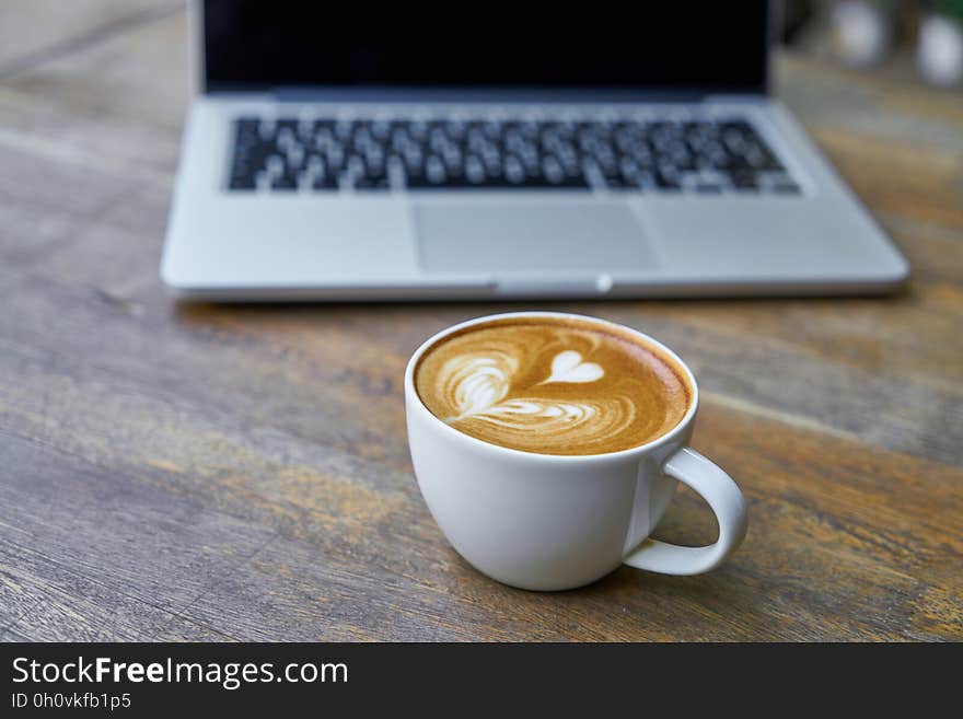 A cup of cappuccino and laptop computer.