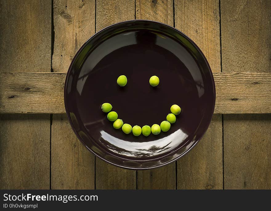 Beans in shape of smiling face on brown plate on rustic wooden table. Beans in shape of smiling face on brown plate on rustic wooden table.