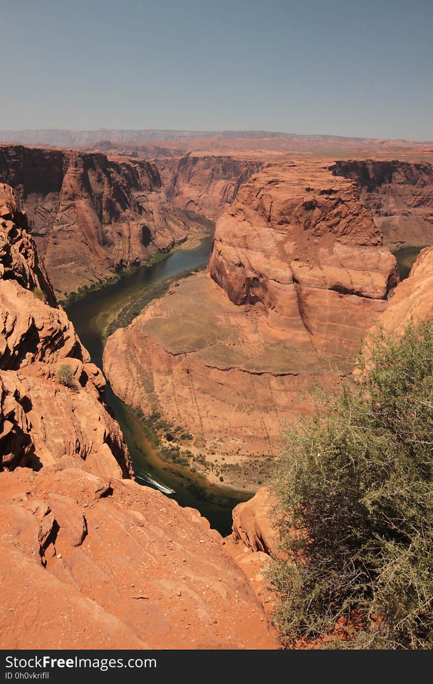 Deep river canyon cut through landscape composed mostly of red sandstone, pale blue sky. Deep river canyon cut through landscape composed mostly of red sandstone, pale blue sky.