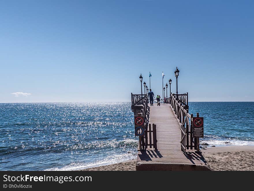 Wooden boardwalk and pier on waterfront on sunny day. Wooden boardwalk and pier on waterfront on sunny day.