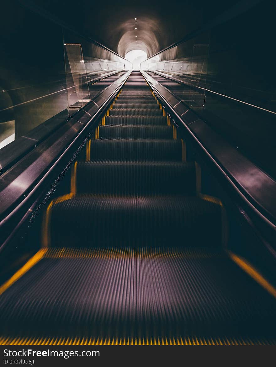 A long escalator leading in and out from a subway station. A long escalator leading in and out from a subway station.