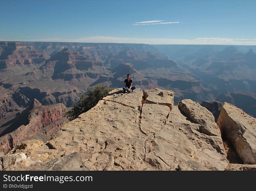 A person sitting on the precipice at the Gran Canyon.