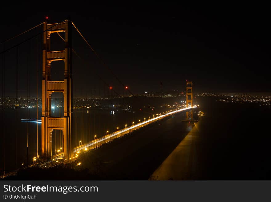 Aerial over Golden Gate Bridge, San Francisco, California illuminated at night with distant city skyline. Aerial over Golden Gate Bridge, San Francisco, California illuminated at night with distant city skyline.