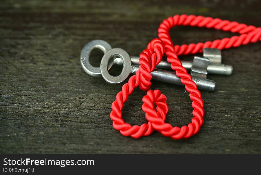 Close up of red nylon rope over silver keys on rustic wooden table. Close up of red nylon rope over silver keys on rustic wooden table.