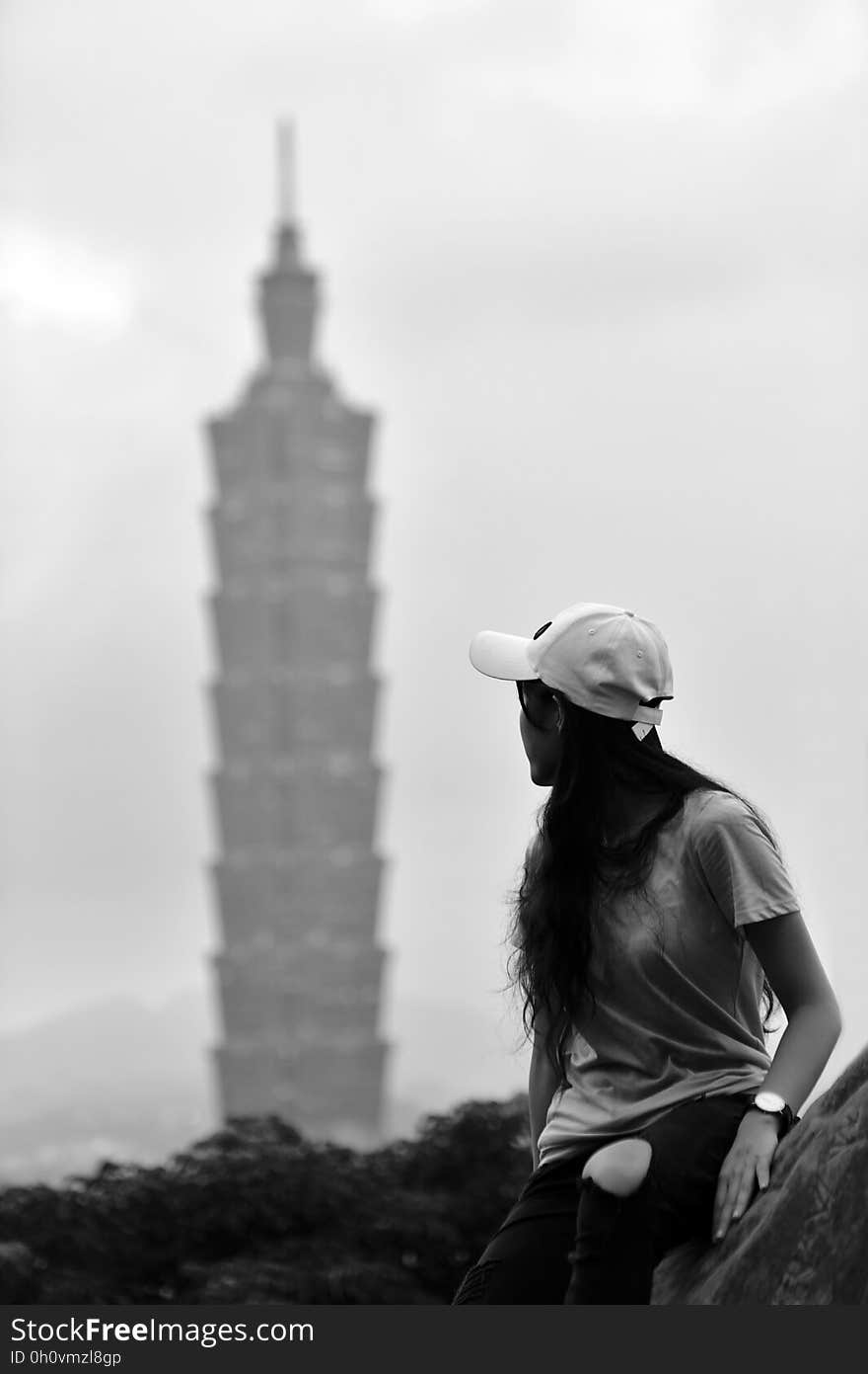 Woman looking back at high rise tower in distance in black and white. Woman looking back at high rise tower in distance in black and white.