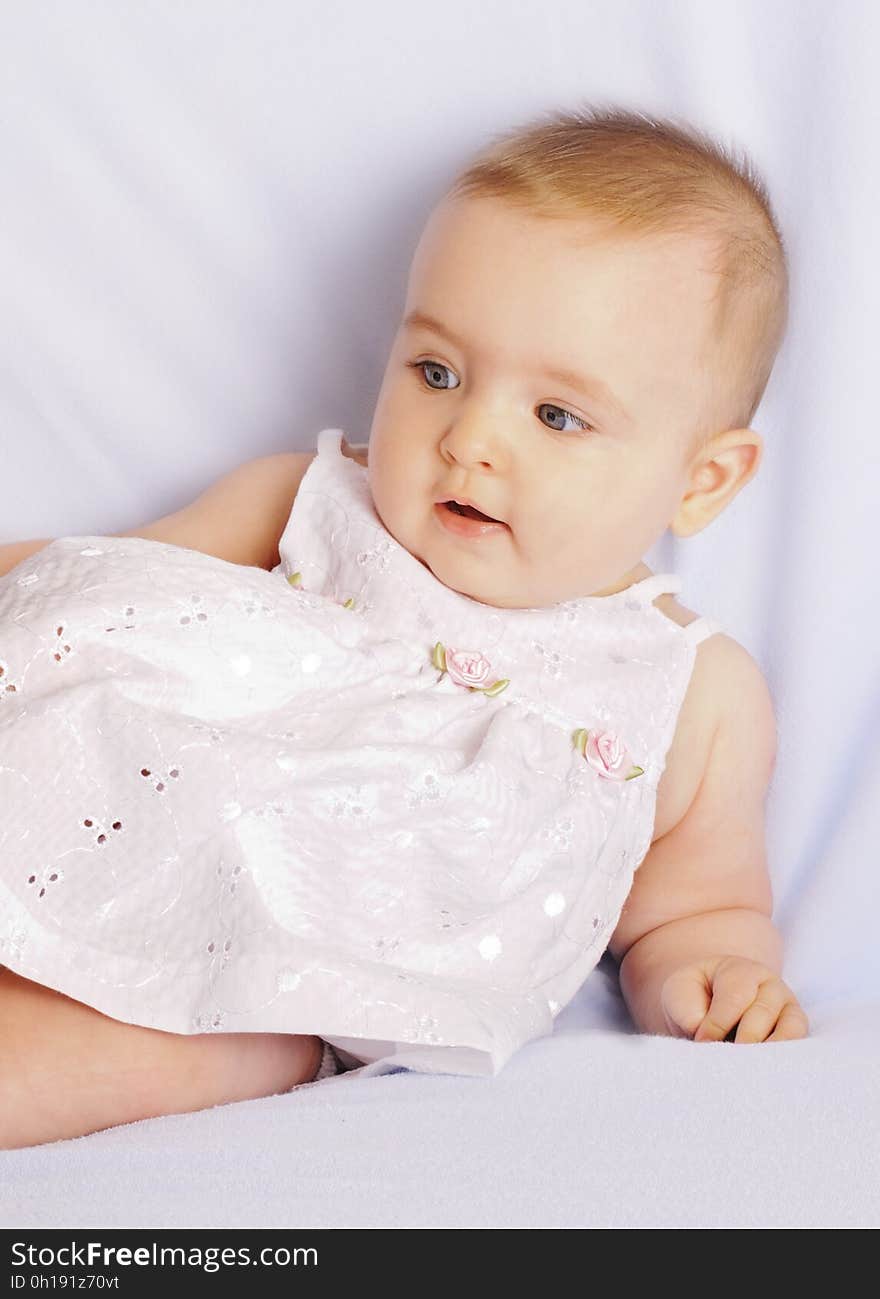 A baby girl wearing a white dress.