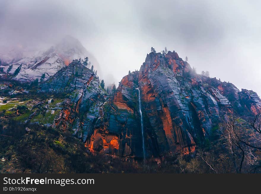 A red mountain with clouds above.