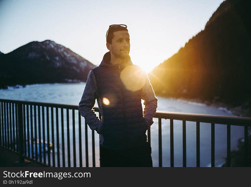 A man on a viewing platform next to a mountain range. A man on a viewing platform next to a mountain range.