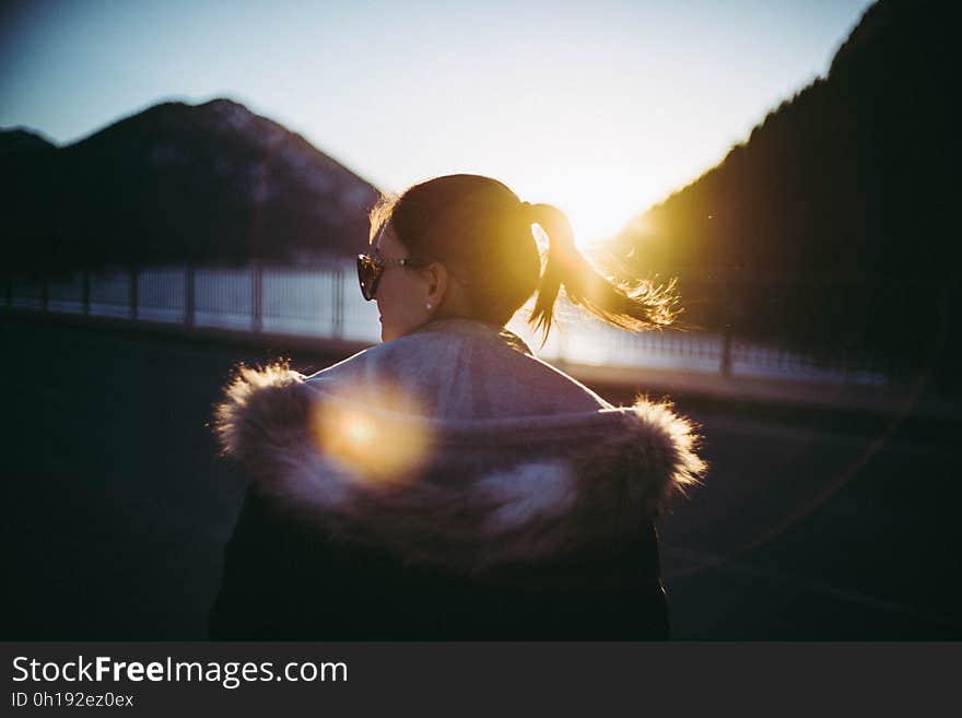 A girl on a viewpoint looking at sun setting between mountains. A girl on a viewpoint looking at sun setting between mountains.