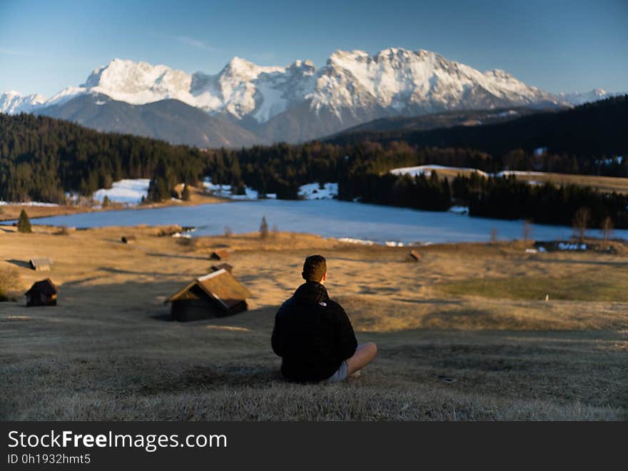 Hiker sitting on shores of alpine lake in Bavaria, Germany on sunny day,. Hiker sitting on shores of alpine lake in Bavaria, Germany on sunny day,