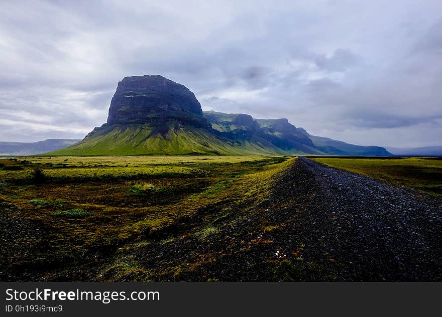 Rock formation in green rural field against cloudy skies in daytime. Rock formation in green rural field against cloudy skies in daytime.