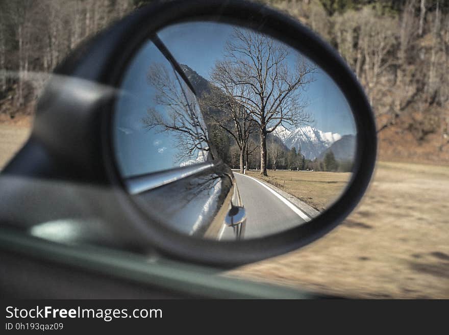 Mountains and trees reflecting in rear view mirror on car on sunny day. Mountains and trees reflecting in rear view mirror on car on sunny day.