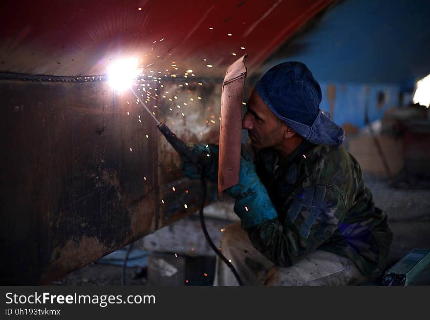 Man Holding Welding Rod and Welding Mask While Working