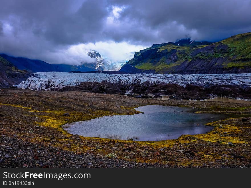 Pool of water in rural fields under cloudy skies. Pool of water in rural fields under cloudy skies.