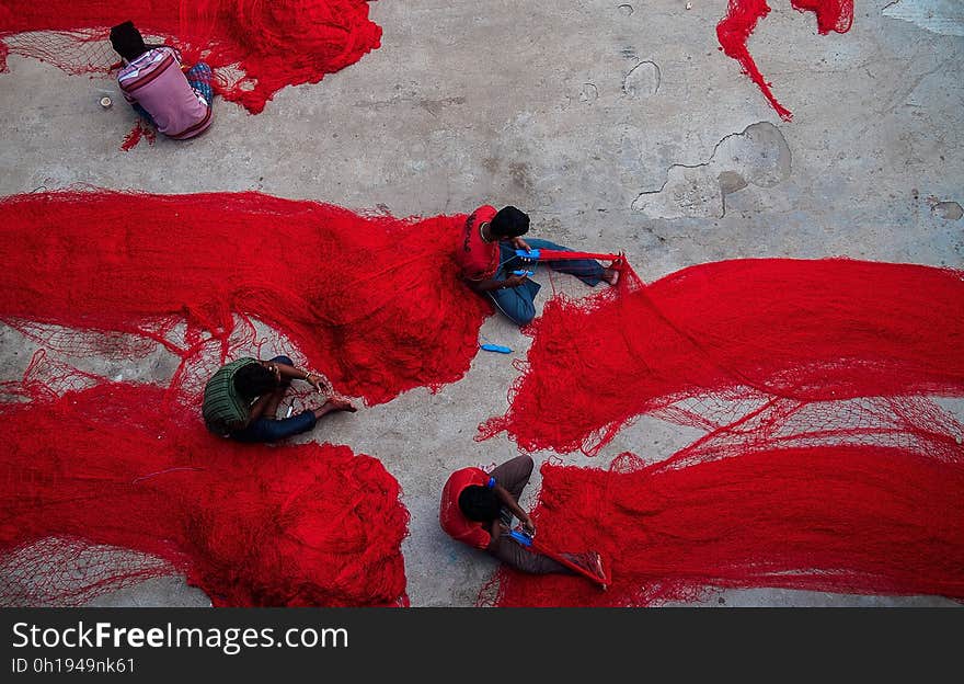 Aerial view of fishermen working on red nylon nets. Aerial view of fishermen working on red nylon nets.