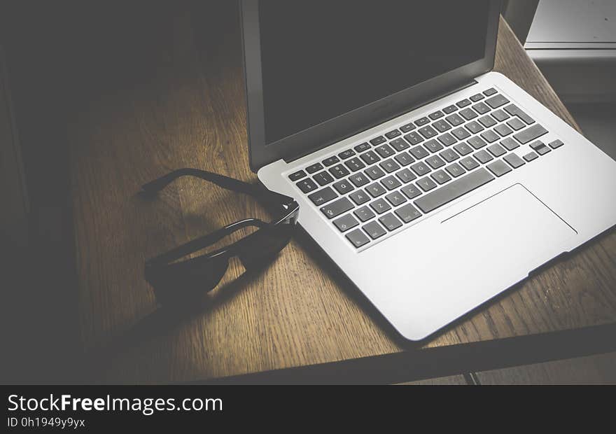 A pair of sunglasses next to a laptop computer. A pair of sunglasses next to a laptop computer.