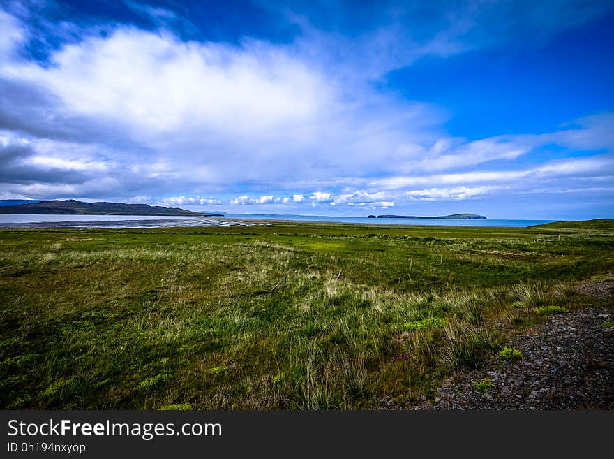 A landscape with green fields and mountains in the distance.