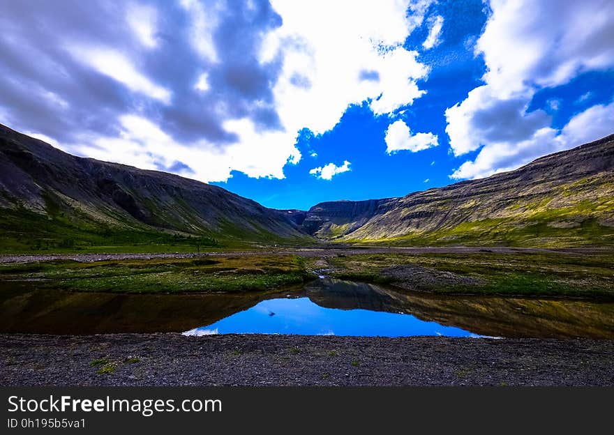 Blue skies reflecting in lake in field of mountain valley countryside on sunny day.